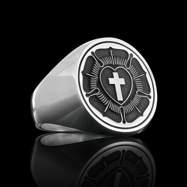 Custom silver signet ring featuring a cross inside a heart, displayed on a sleek black background.