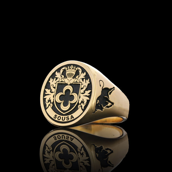 Sousa family gold signet ring with a detailed crest and bull engraving, displayed on a sleek black surface.