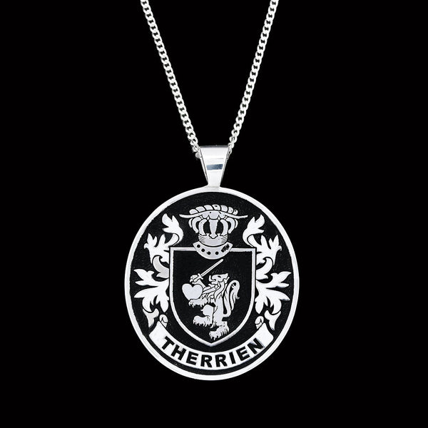 A silver pendant featuring the Therrien family crest, with a lion holding a heart, displayed on a chain.