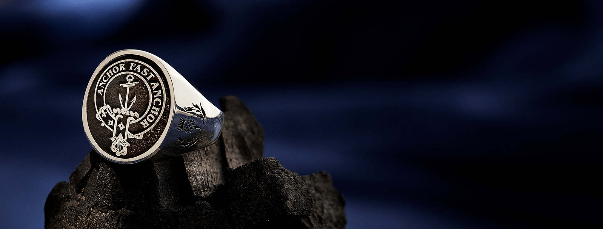 A sterling silver clan crest ring engraved on a textured background.