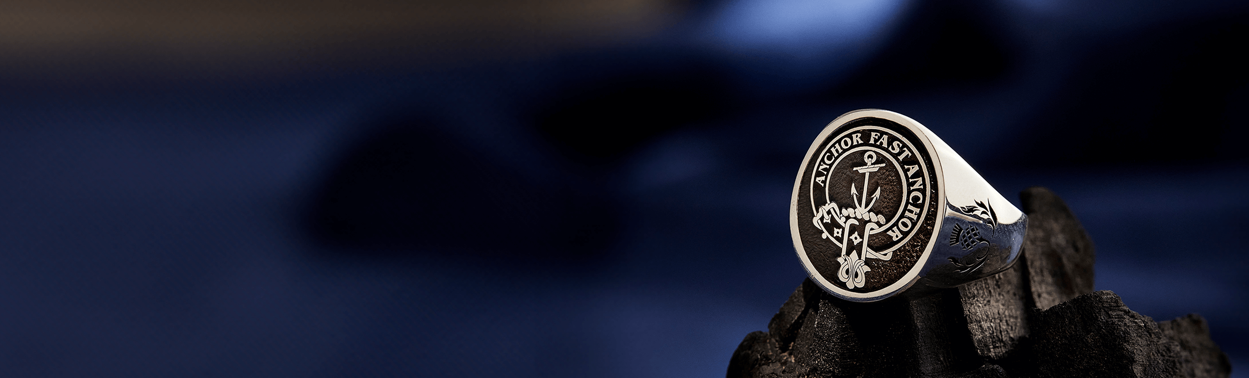 A sterling silver clan crest ring engraved on a textured background.