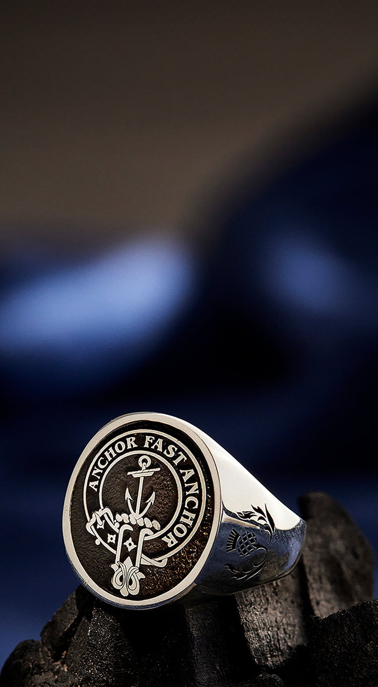 A sterling silver clan crest ring engraved on a textured background.