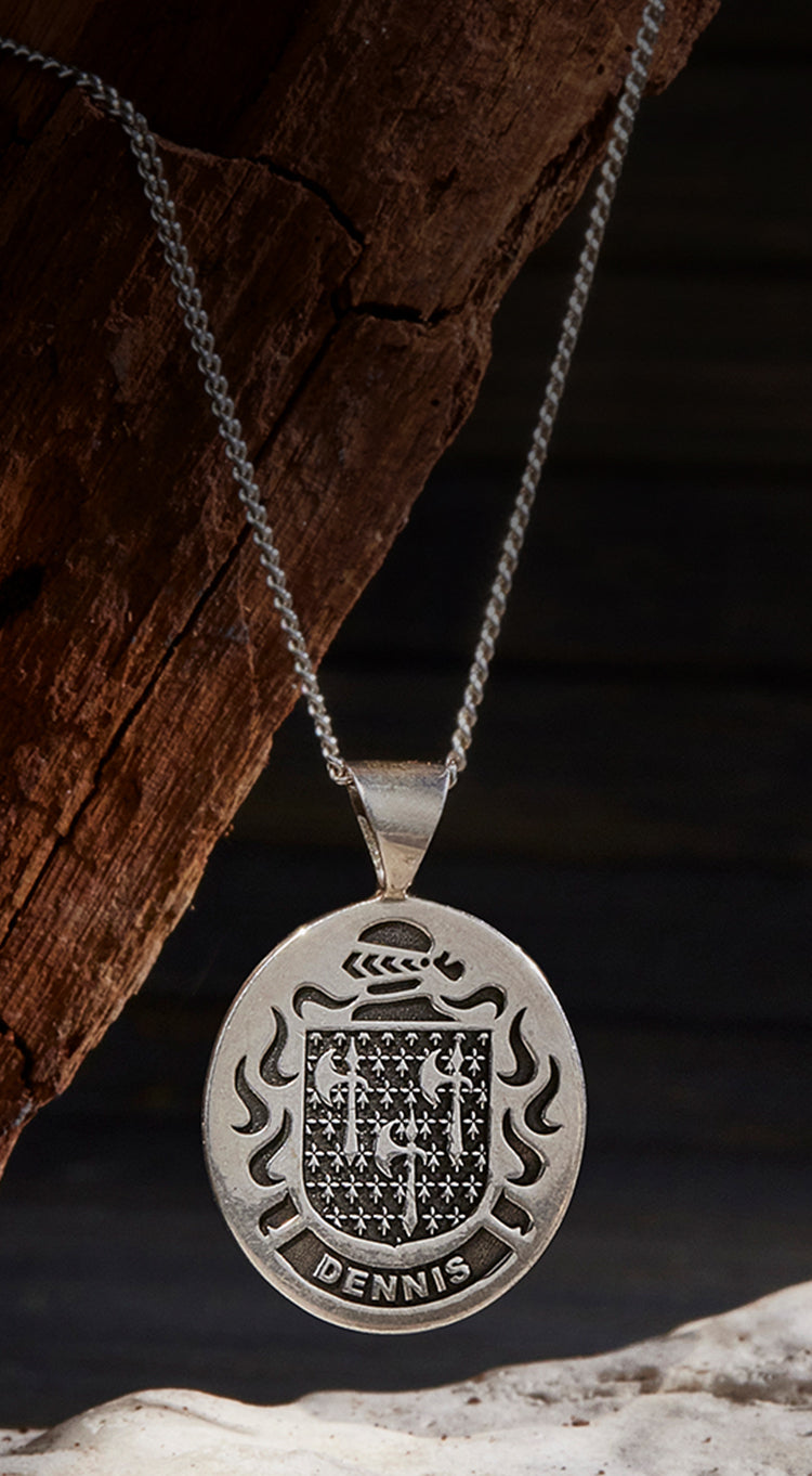 A double-sided sterling silver pendant engraved with a family crest and name.