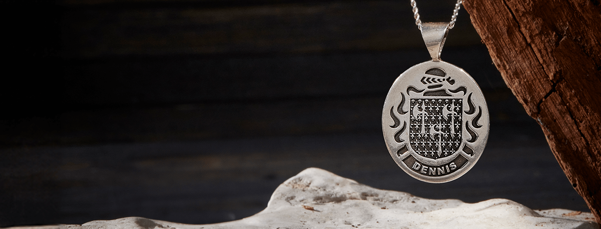 A double-sided sterling silver pendant engraved with a family crest and name.