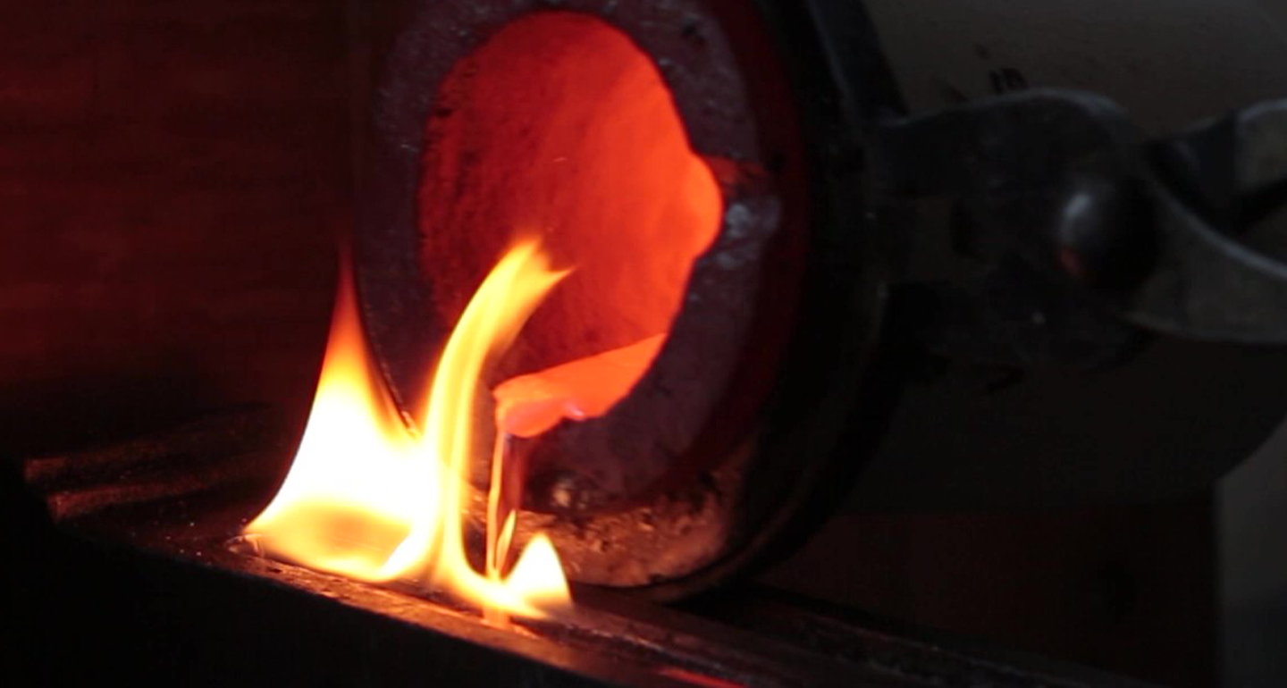 Molten metal pouring from a glowing crucible surrounded by fire.