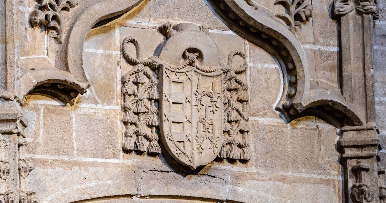 A detailed stone carving of an ornate heraldic crest on a historic building facade.