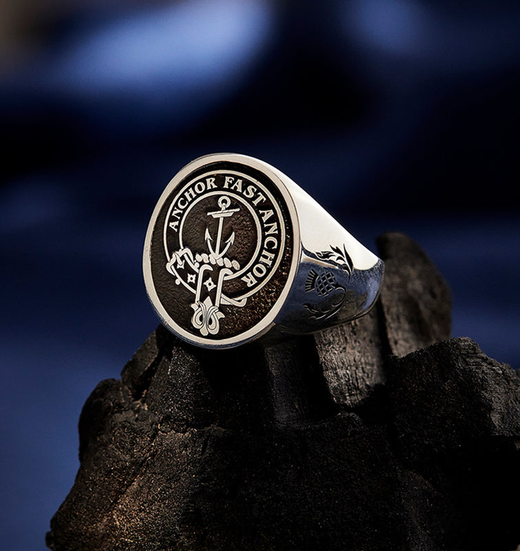 A sterling silver clan crest ring engraved on a textured background.