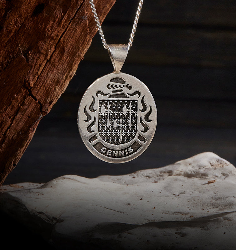 A double-sided sterling silver pendant engraved with a family crest and name.