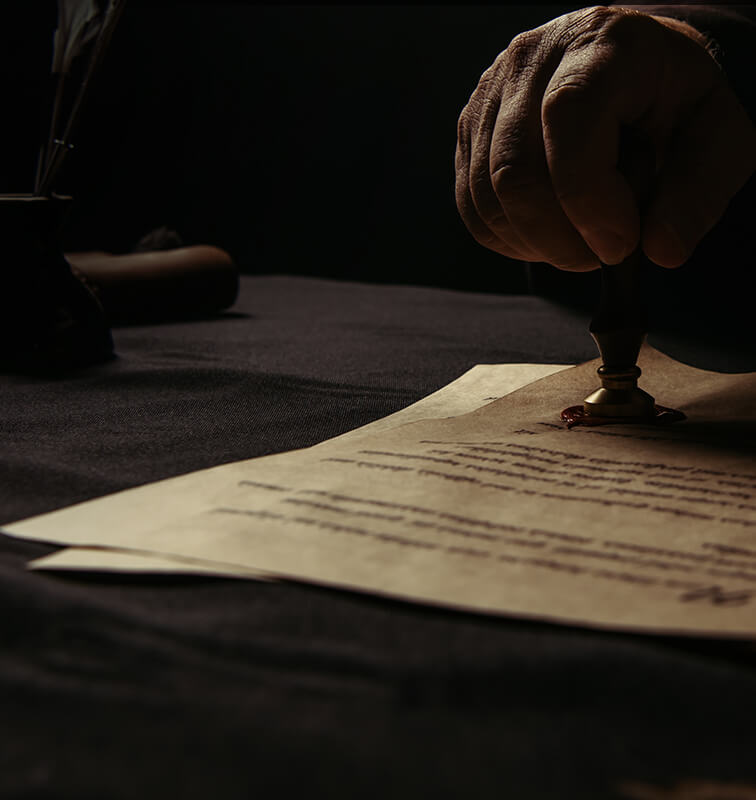 Dark background with a hand sealing a document using wax, evoking a historic and official atmosphere.