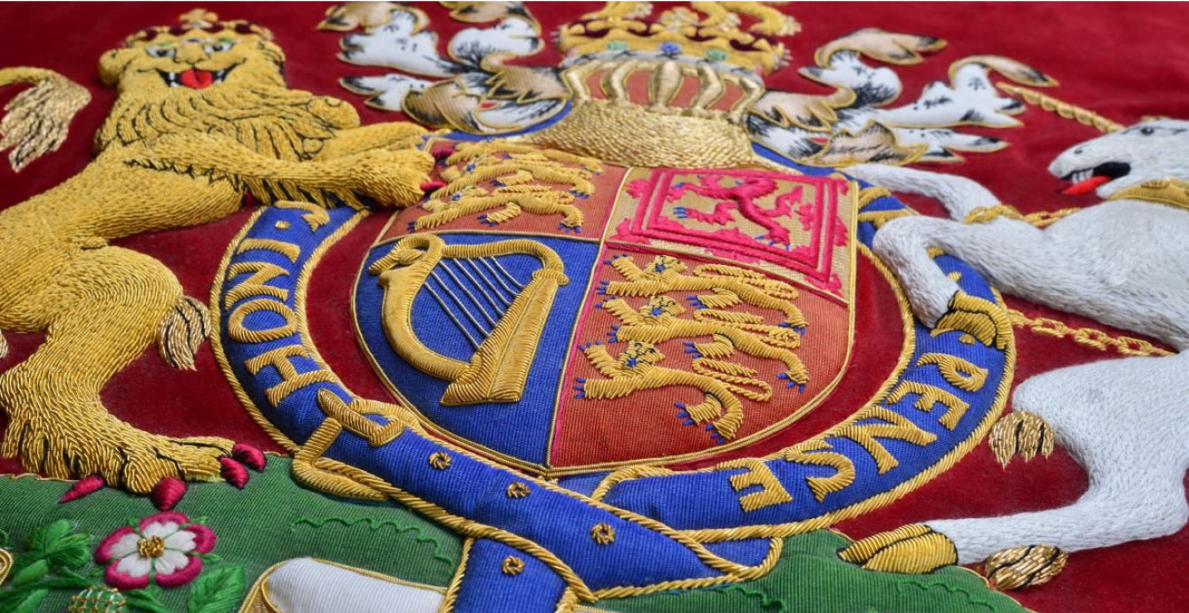 Close-up of an embroidered crest with a harp and lions on red and blue fabric.