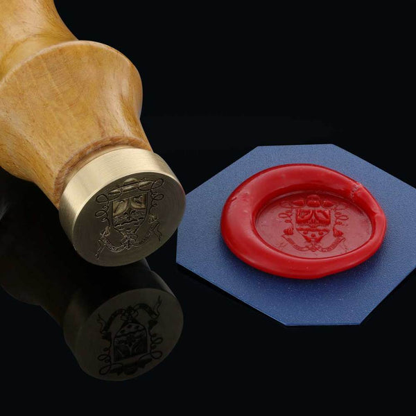 A wooden wax seal stamp engraved with a crest, shown alongside a red wax imprint of the same design.