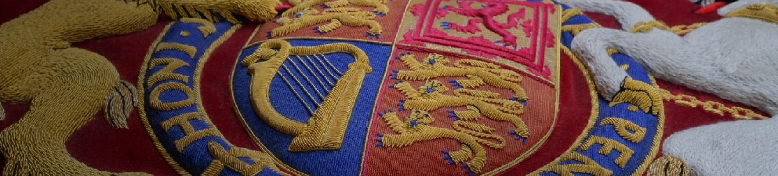 Close-up of an embroidered crest with a harp and lions on red and blue fabric.